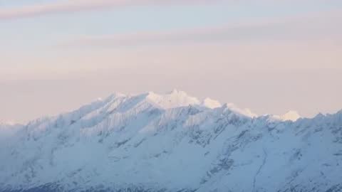 Dawn Alpenglow Revealing Snow-Covered Alpine Ridge and Jagged Peaks in Soft Pastel Light