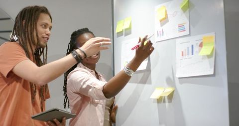 Young diverse team collaborating at whiteboard marking visual charts and planning strategy