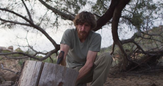 Man Cutting Wood in Wilderness Using Axe Under Tree - Download Free Stock Images Pikwizard.com