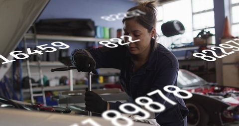 Female mechanic tightening engine bolts with socket wrench in garage, numeric overlay