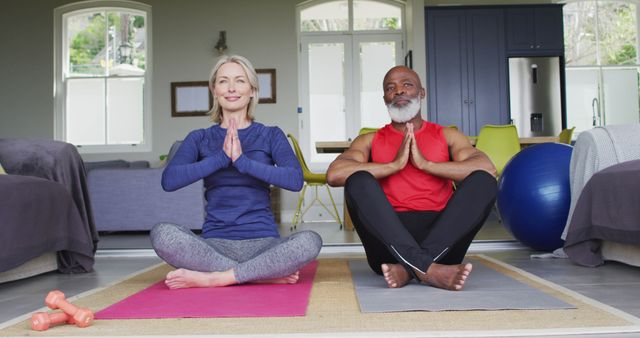 Elderly man and woman practising yoga in living room, demonstrating healthy lifestyle and mindfulness. Useful for promoting senior wellness, fitness programs, yoga classes, and healthy living content aimed at mature audiences.