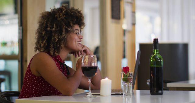 Biracial woman having a romantic dinner blowing kisses on image chat at home. out and about during coronavirus covid 19 pandemic.