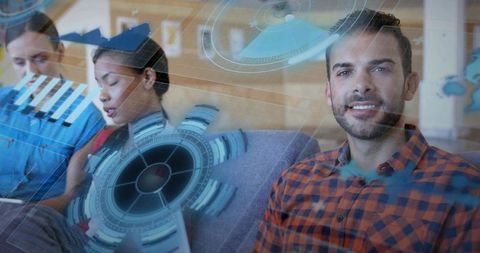 Smiling man wearing orange plaid shirt using tablet with holographic ui in coworking lounge