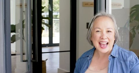 Senior Woman Smiling Warmly While Opening Glass Door