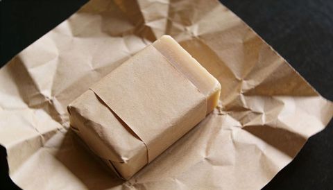 Handmade soap wrapped in kraft paper showing rustic folds, natural texture and shadow