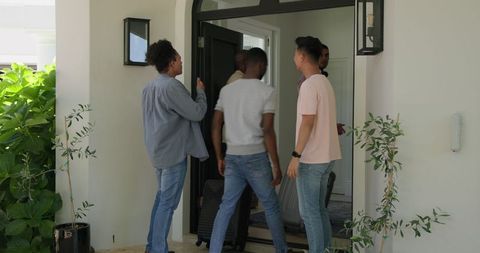 Friends arriving at door with luggage for wedding celebration