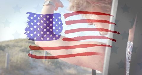 Woman leaning from car raising arm with american flag overlay on coastal drive