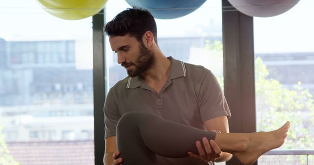 Physical therapist assisting patient with leg exercise during rehabilitation session. Ideal for use in health and wellness blogs, medical professional advertisements, physical therapy clinics, and educational materials about rehabilitation services.