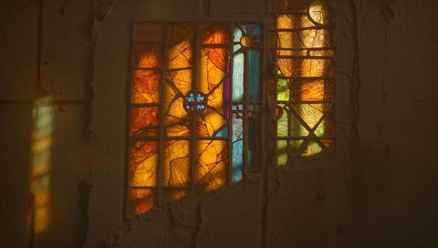 Sunlight through broken stained glass lighting chapel walls