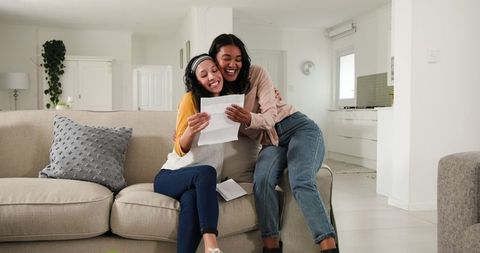 Two women sharing exciting news while reading documents at home