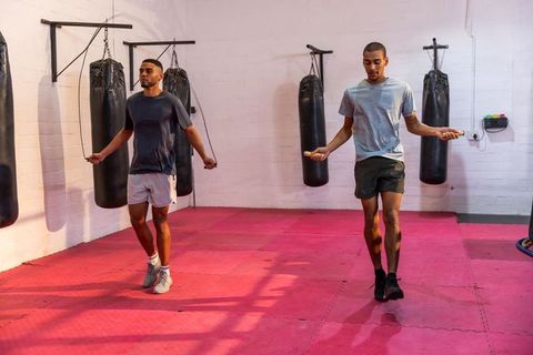 African american men jumping rope in boxing gym training cardio with punching bags