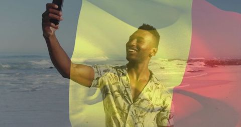 Smiling man taking selfie on sunny beach with tricolor flag overlay