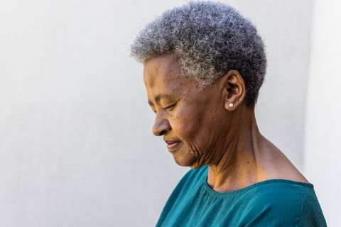 Senior african woman in profile contemplating life, pearl earrings, teal top, minimalist