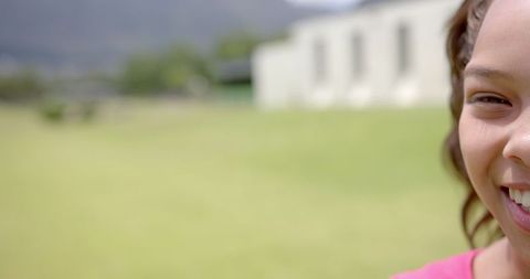 Close-Up of Smiling Biracial Girl with Green Field Background