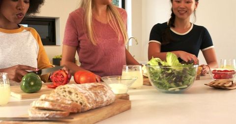Diverse Women Preparing Fresh Salad Together in Modern Kitchen