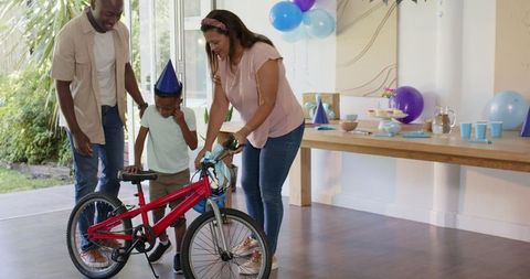 Family Celebration with Young Boy Receiving New Bicycle at Home