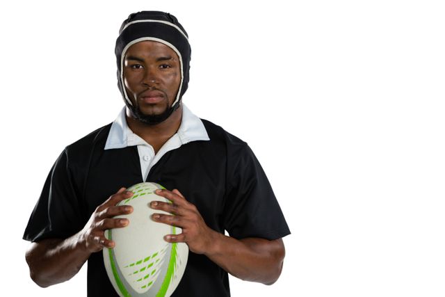 Portrait of male rugby player wearing helmet holding ball while standing against white background