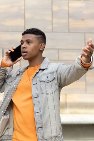 African american teen talking on smartphone and gesturing in urban street portrait