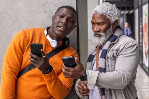 African american men of different generations checking phones in urban transit corridor
