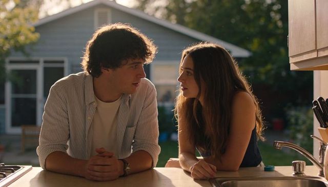 Sunlit young couple leaning on kitchen counter sharing intimate conversation in backyard