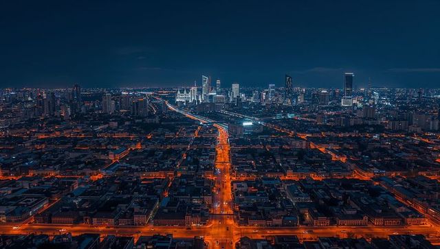 Leading arterial road drawing eye to downtown skyline night aerial with light trails