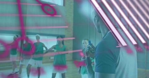 Basketball coach briefing team during gym practice under neon glass with stopwatch