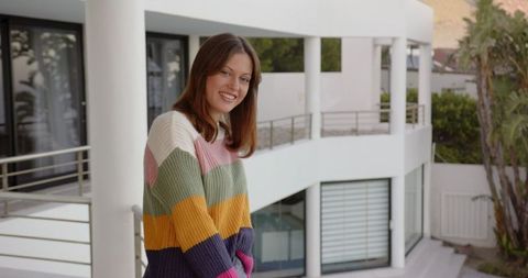 Smiling woman in colorful sweater on modern terrace