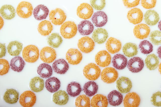 An overhead view depicting multicolor cereal rings floating in milk, signifying a breakfast concept with vibrant hues. Ideal use for food blogs, healthy breakfast promotions, dairy advertisements, and children's meal plans.