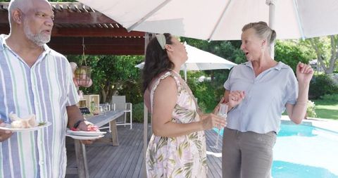 Senior Friends Enjoying Poolside Party in Garden Setting