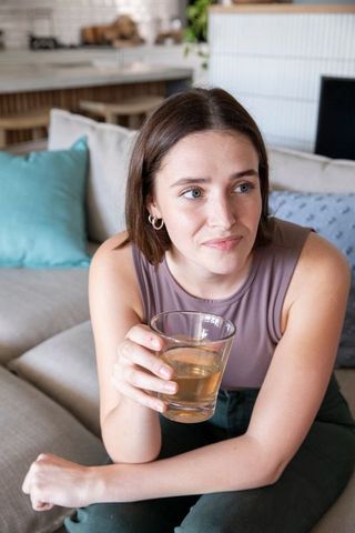 Woman sipping beverage on comfortable sofa in modern living space