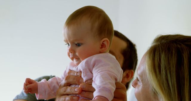 Father Lifting Baby While Mother Watches in Background - Download Free Stock Images Pikwizard.com