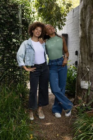 African american friends standing on garden path, smiling and posing in casual denim