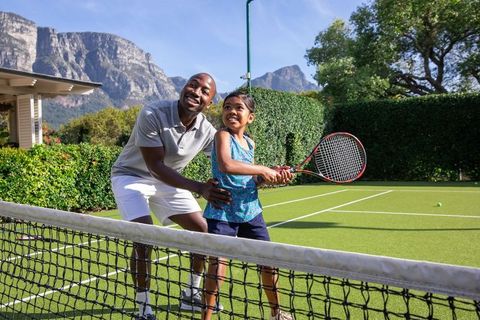 Father Teaches Daughter Tennis Swing on Sunny Court