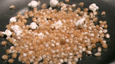 Close-Up of Popcorn Kernels Popping in Oil in Slow Motion