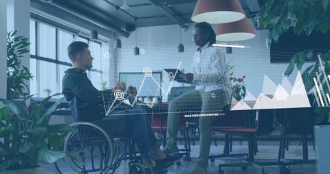 Inclusive team discussing data with wheelchair user and holographic analytics in workspace