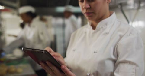 Chef Using Tablet in Busy Professional Restaurant Kitchen