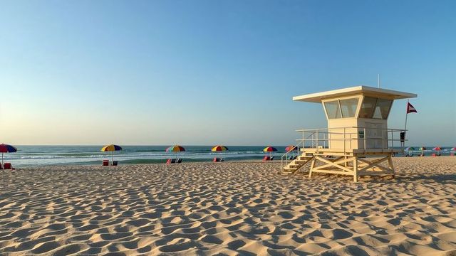 Sunny beach with lifeguard tower and colorful umbrellas at sunrise
