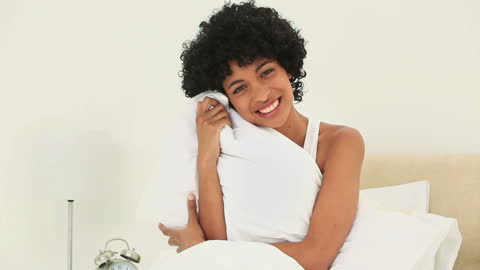 Joyful Woman Embracing Pillow with Morning Light