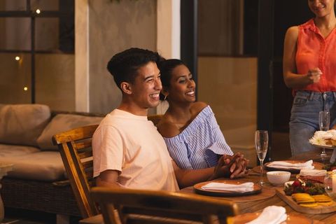 Asian man and african american woman holding hands during cozy candlelit dinner