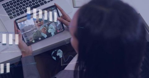 Professional woman holding tablet during virtual meeting with coworker and data overlays