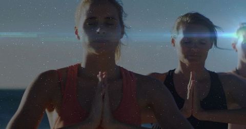 Sunlit shoreline yoga trio practicing mindful meditation with lens flare silhouettes