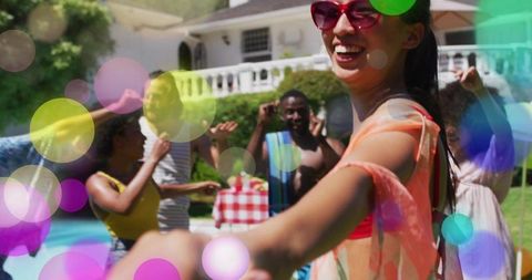 Smiling woman reaching forward at colorful summer backyard pool party with friends