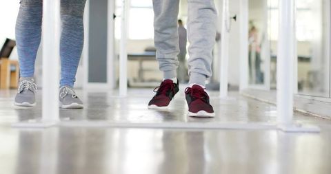 Walking through parallel bars during gait training in bright rehabilitation studio