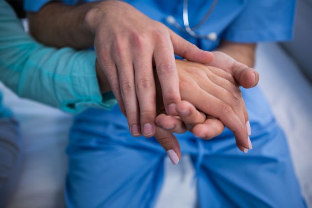 This image shows a doctor providing emotional support to a patient by placing their hand on the patient's hand. It is ideal for use in healthcare-related articles, medical websites, patient care brochures, and any content focusing on compassion and empathy in the medical field.