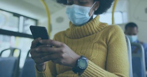 Commuter wearing mask on bus using smartphone