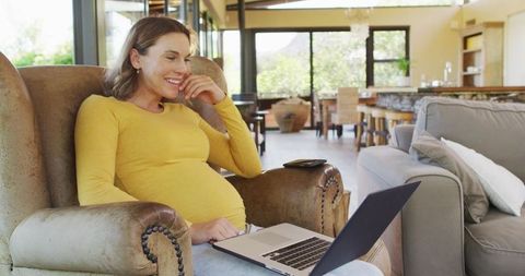 Pregnant Woman Relaxing with Laptop in Cozy Living Room