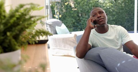 African American Man Talking on Smartphone Relaxing Indoors