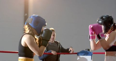 Intense Female Boxers Sparring While Coach Observing in Indoor Boxing Ring