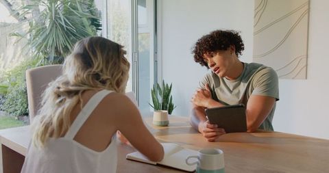 Young Couple Discussing Ideas with Tablet and Notebook