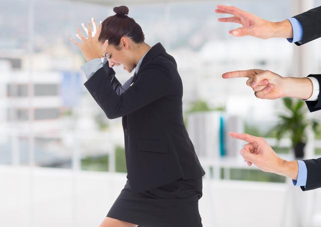 Image depicts a businesswoman in a corporate setting, visibly stressed and frustrated, with multiple hands pointing at her. This image can be used to illustrate workplace stress, criticism, and the pressures of a corporate environment. Suitable for articles on mental health, workplace dynamics, and professional challenges.
